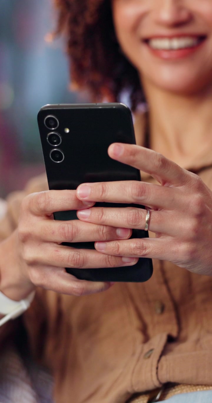 Donna sorridente che usa lo smartphone in un ambiente informale
