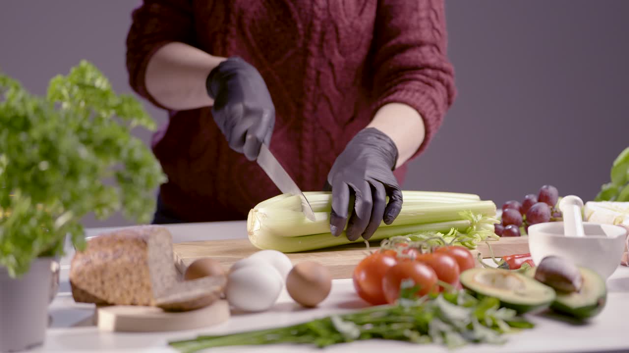 A chef slices fresh celery with a sharp knife, focusing on precision. The scene showcases professional food prep, featuring organic vegetables, fresh ingredients, and a clean, organized cooking space