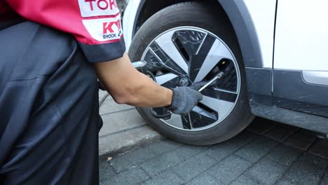 person inspecting and maintaining a car tire