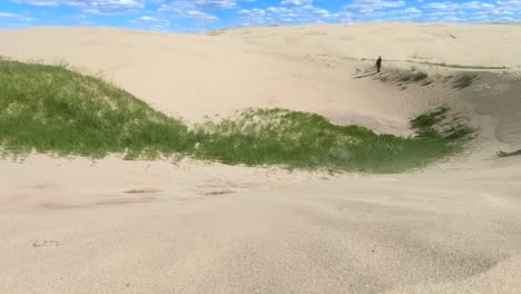 persona de pie en la arena del desierto en un día ventoso y soleado con nubes en el cielo