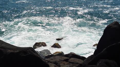 HD-Slow-motion-Hawaii-Kauai-static-of-ocean-waves-crashing-with-some-ocean-spray-with-lava-rocks-in-foreground