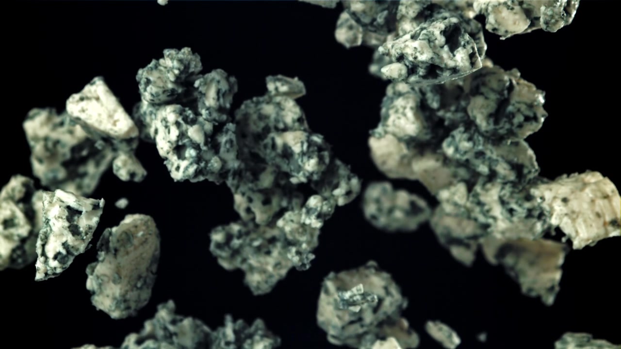 Blue Cheese Pieces Falling in Slow Motion on Black Background
