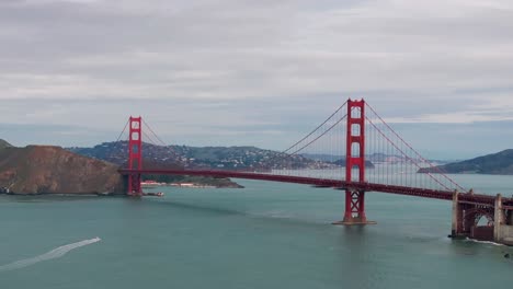 drone aerial view of the golden gate bridge with a boat going underneath it