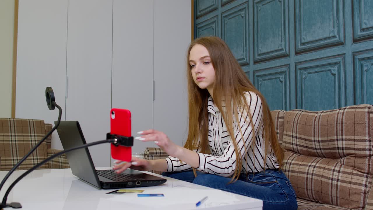 Smiling young business woman professional working on phone using laptop sit at home office desk