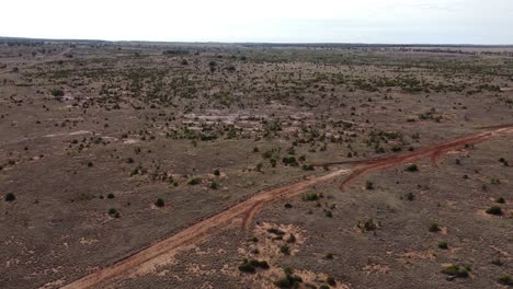 Drone-flying-over-unsealed-roads-and-power-lines-in-a-desert-style-landscape