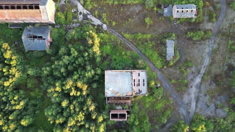 slow aerial fly-over of a disused coal mining complex that has been overgrown with trees