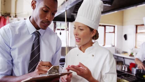 el gerente escribe en el clipboard mientras explica al chef