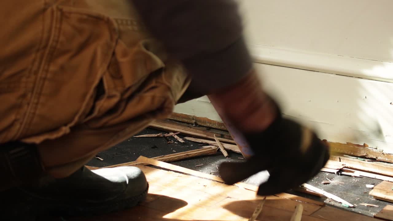 Tight Shot of a Hard Working Man Using a Pry Bar to Remove Water Damaged Wood Flooring