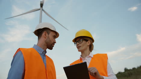 close-up view of two caucasian male and female engineers discussing some problems at the wind station of renewable energy