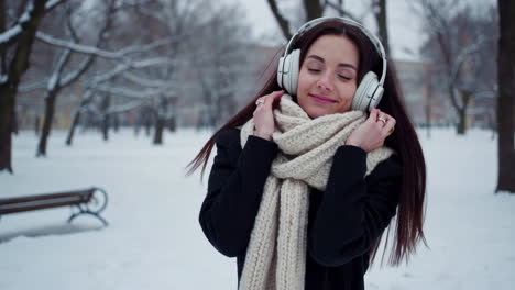 young woman enjoys music in a snowy winter park