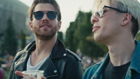 two young caucasian men having fun on music festival while drinking beer.