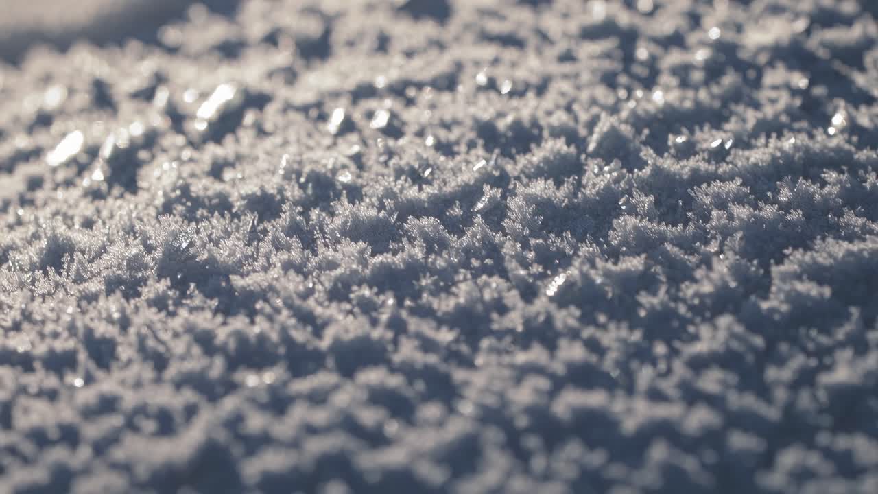 Close-up, low-angle video of frost-covered ground, capturing the intricate details of ice crystals