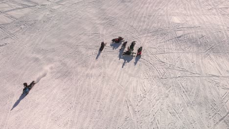 Aerial-overhead-view-of-a-group-of-people-riding-snowmobiles-on-the-snow