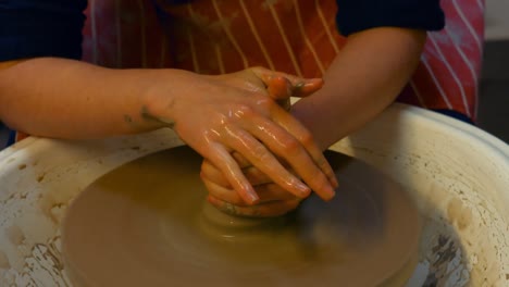 hands of male potter assisting female potter