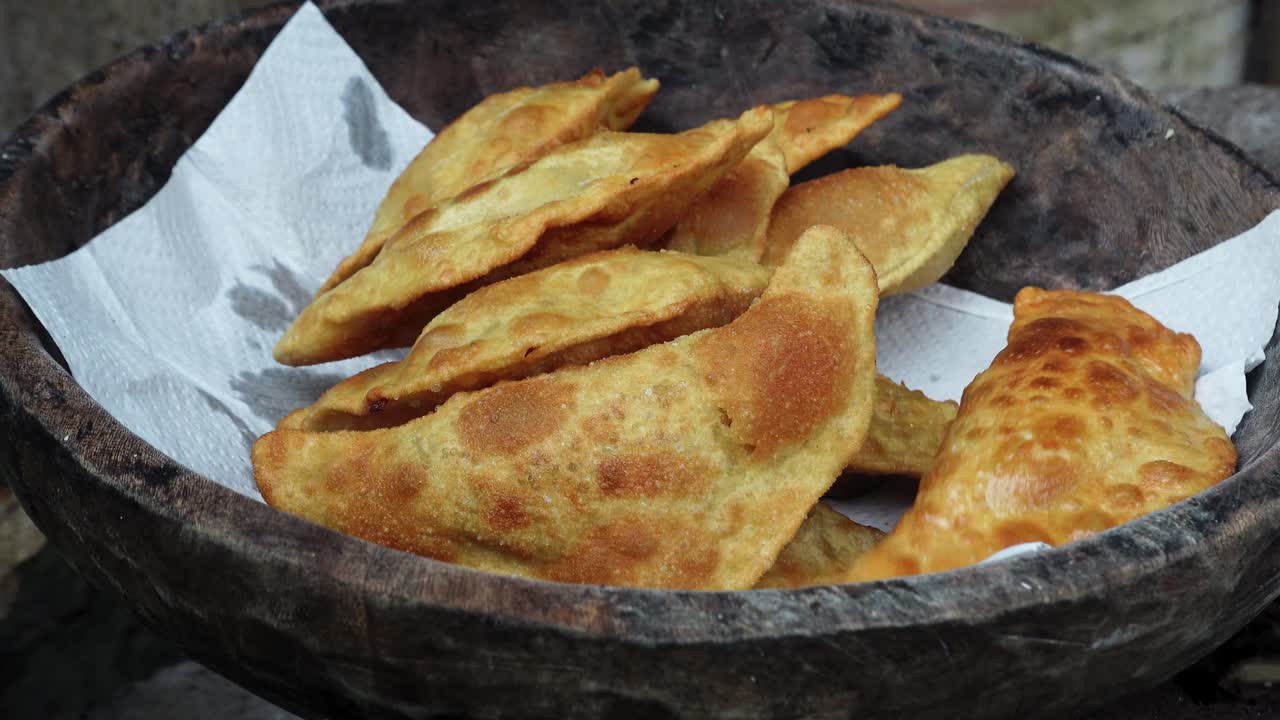 las empanadas recién fritas se sirven en un cuenco de madera