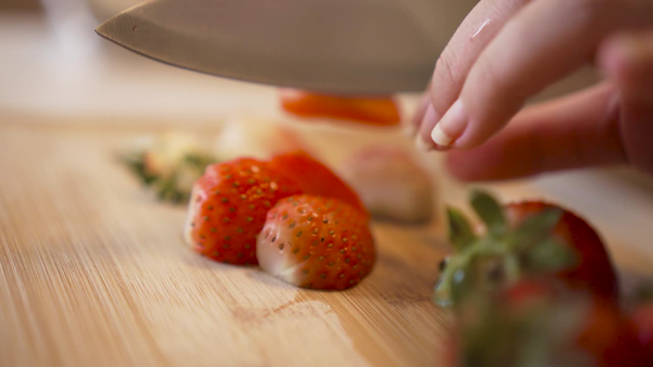 manos femeninas cortando fresas maduras frescas en una tabla de cortar