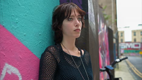 close up outdoor fashion portrait of young alternative style woman leaning against graffiti covered wall in london city street uk in real time 3