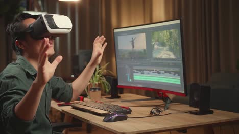 asian male video editor using a vr headset while works with footage and sound on his personal computer, he works late at night