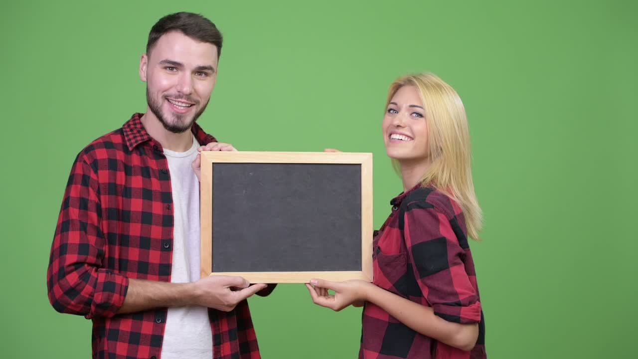 Young happy couple holding blackboard together