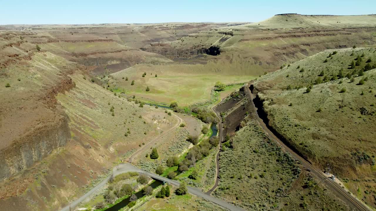US, Oregon, Madras, Trout Creek, 2025-04-19 - Drone view of the creek that cuts the canyon on the left, and the railroad tracks cut into the cliff face on the right.