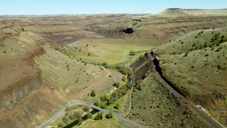 us, oregon, madras, trout creek, 2025-04-19 - drone view of the creek that cuts the canyon on the left, and the railroad tracks cut into the cliff face on the right.