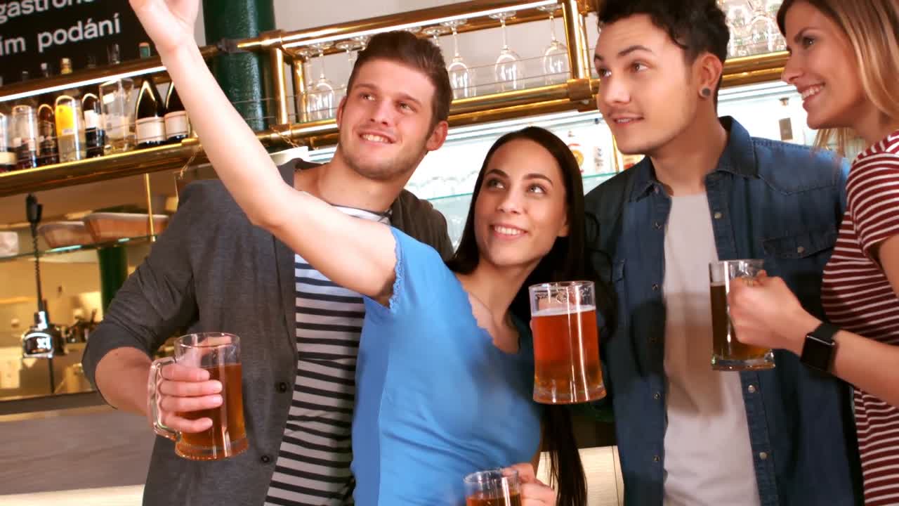 amigos tomando selfies con el teléfono móvil mientras beben un vaso de cerveza