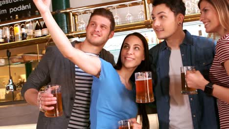 friends taking selfie from mobile phone while having a glass of beer