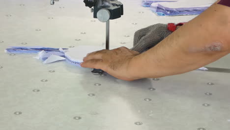the commercial textiles worker works on the machine cutting a pile of fabric at the clothing factory