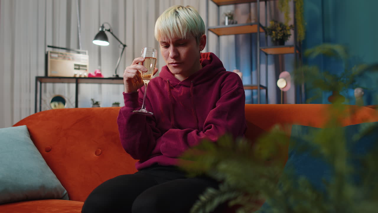 mujer llorando mientras bebe champán en el sofá