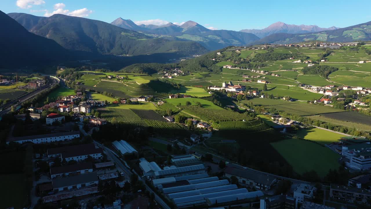 Drone panning up revealing Austrian Alps with village and green grass fields during sunny summer day between Austria and Germany in 4k