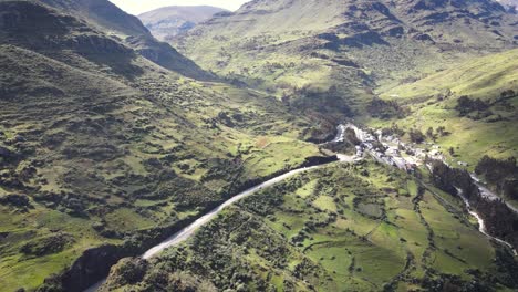 Drone-shot-of-a-car-in-a-road-in-the-middle-of-green-rocky-mountains-in-a-valley-in-Huaraz-Peru