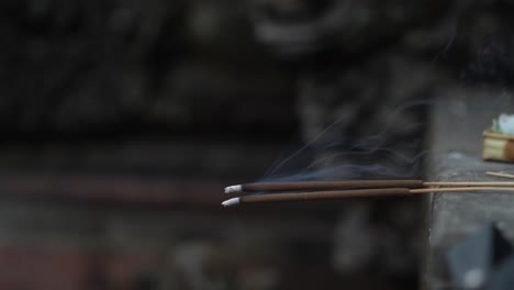 two incense sticks burning with smoke rising against a blurred background with a sense of calm and spirituality