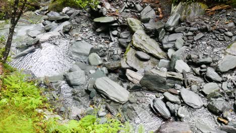 top down shot of tranquil flowing river between rocks and stones in nature during sunny day,close up