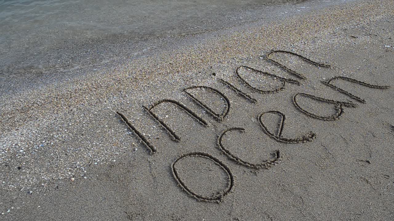 Inscription the Indian Ocean on sand on the beach. Shooting on the beach