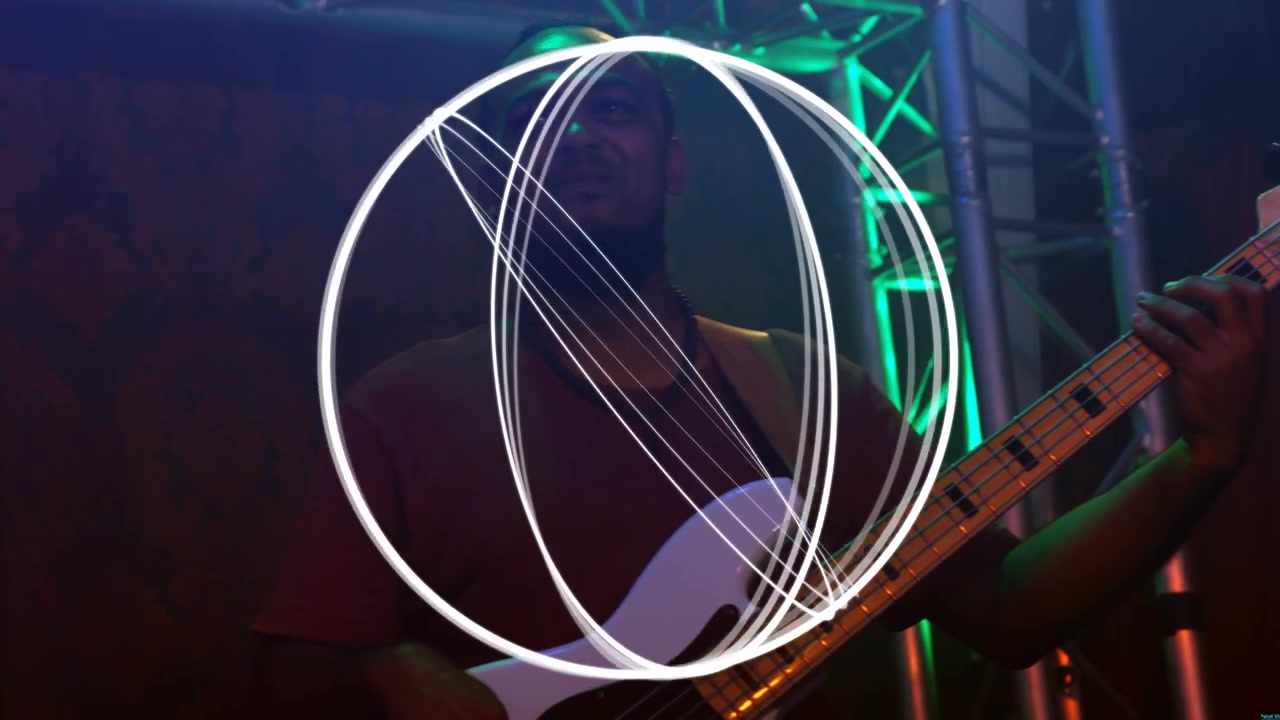 Musicista uomo che suona un basso elettrico bianco su un palco musicale, con una luce brillante che appare e illumina il basso