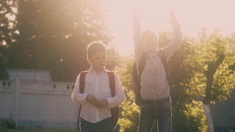 happy boys with coloured bags throw books and give high five