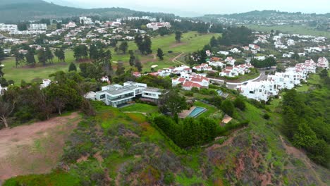 aerial orbiting over mansion at green hillside, exclusive condominium in maitencillo, chile