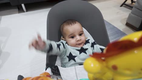 Charming-scene-of-a-4-month-old-engaging-expressively-in-a-baby-bouncer,-exploring-the-world-of-play-with-delightful-toys