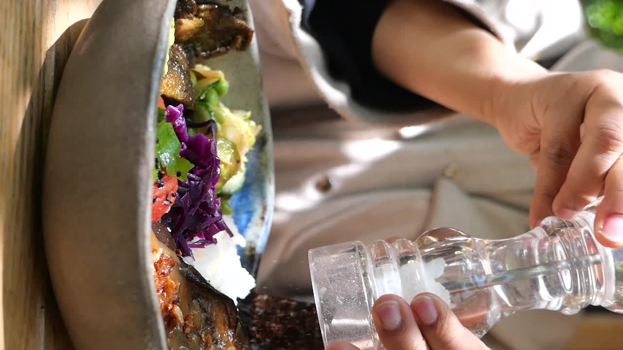 Person Seasoning a Healthy Vegetable Bowl