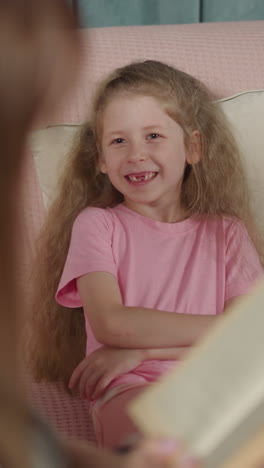 toothless girl and blond boy smile listening to interesting fairytale with happy end. loving mother enjoys reading book to curious children closeup