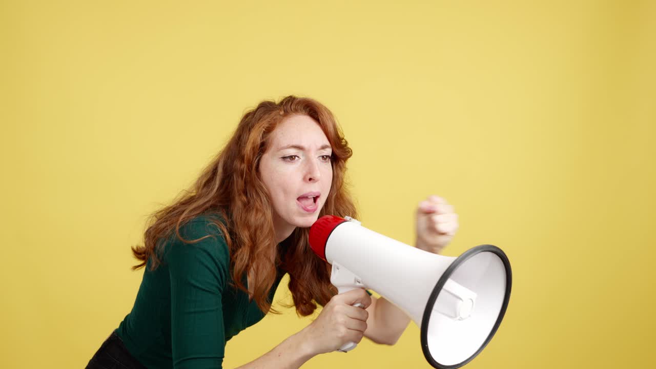 Red-haired woman with a megaphone speaking or shouting on a yellow background