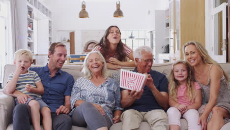 Familia-Multigeneracional-Sentada-En-El-Sofá-De-Casa-Comiendo-Palomitas-De-Maíz-Y-Viendo-Películas-Juntos