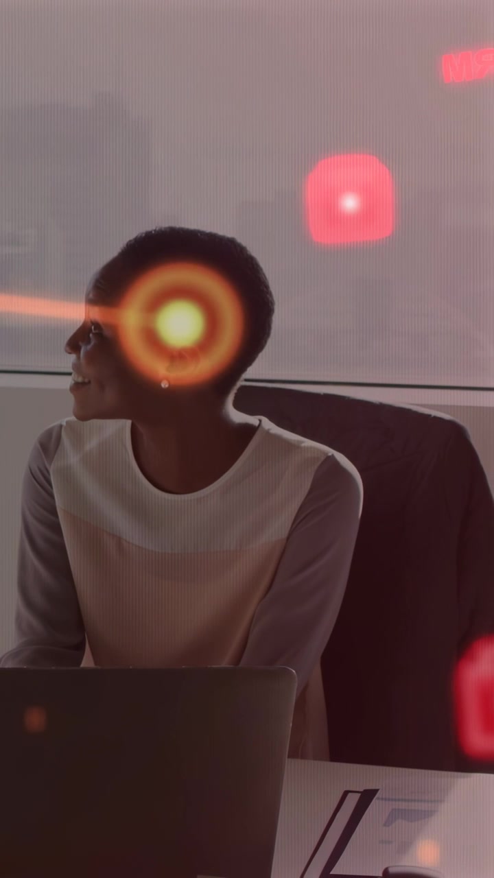 Vertical video: Tech woman turning as red HUD icons drifting over laptop, flare crossing, reacting