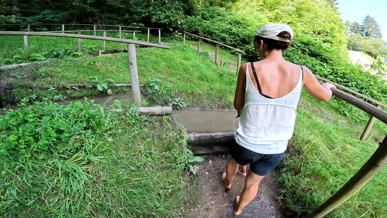 Kvinde der går barfodet i et vandløb i en skov