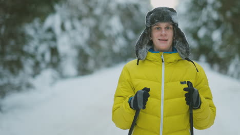 hombre sonriente con esquís y su esposa mirando algo curioso durante el viaje en el bosque invernal