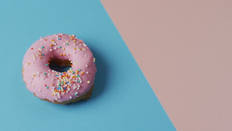 video of donut with icing on blue and pink background