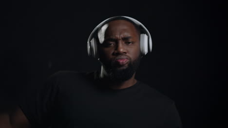 smiling afro guy dancing indoors. portrait of funny african man in headphones