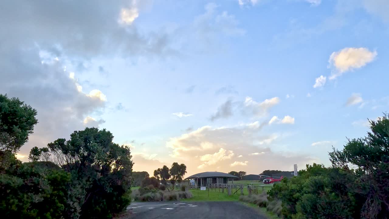 평화로운 일몰이 교외 지역을 가로질러 펼쳐지고, 다채로운 하늘을 배경으로 나무의 실루이 조용한 분위기를 조성합니다.