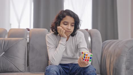 un niño indio molesto incapaz de resolver el cubo de rubik.