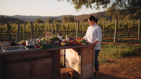 chef prepares fresh ingredients at an outdoor kitchen in a vineyard